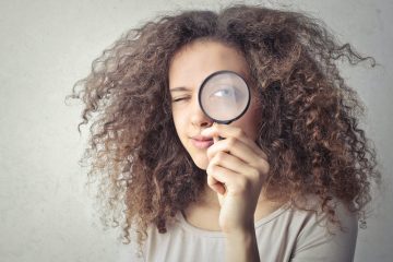 Femme qui regarde vers la caméra avec une grosse loupe devant son œil