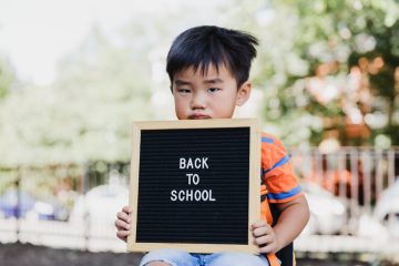 Enfant l'air triste qui tient un panneau "BACK TO SCHOOL"