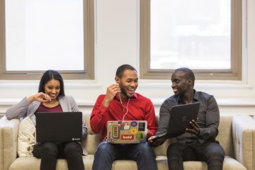 Trois personnes assises sur un canapé avec leurs ordinateurs portables
