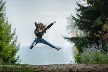Femme qui saute, vue de dos, elle prend une pose en l'air avec un bras pointé vers le ciel