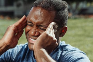 Homme qui se tient les tempes, les yeux fermées et les dents serrées