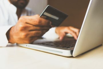 Homme qui regarde sa carte de banque devant son ordinateur portable allumé