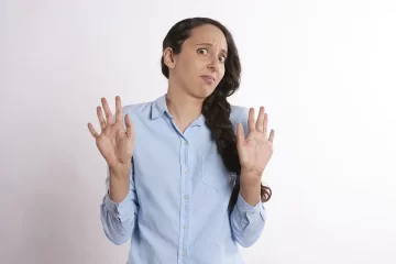 Femme qui tient ses deux mains en l'air (comme pour dire : "je ne veux pas de ça") avec un air dégouté